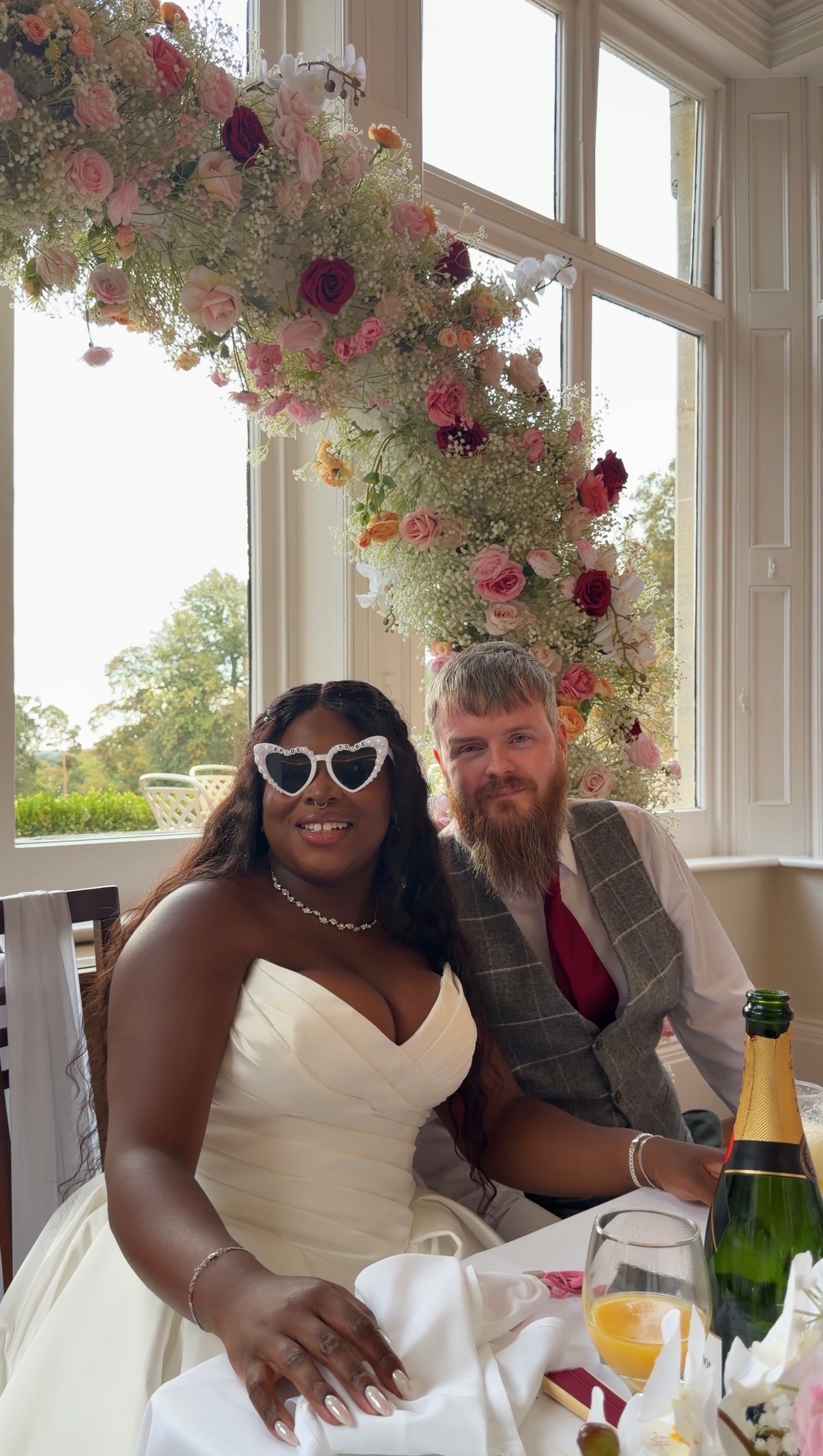 Newlyweds celebrating beneath a pink and white floral arch