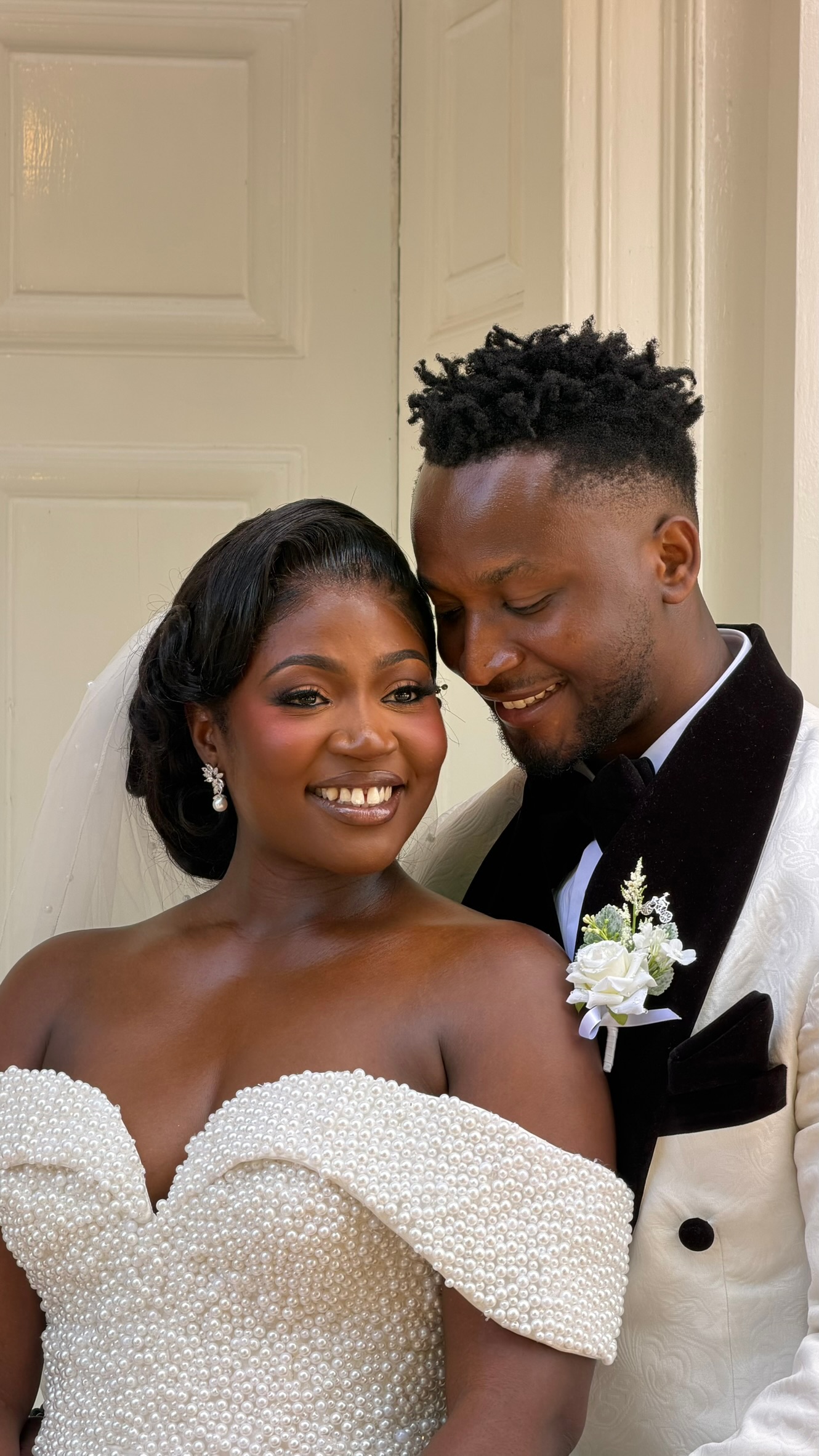 A smiling bride and groom embracing in their wedding outfits